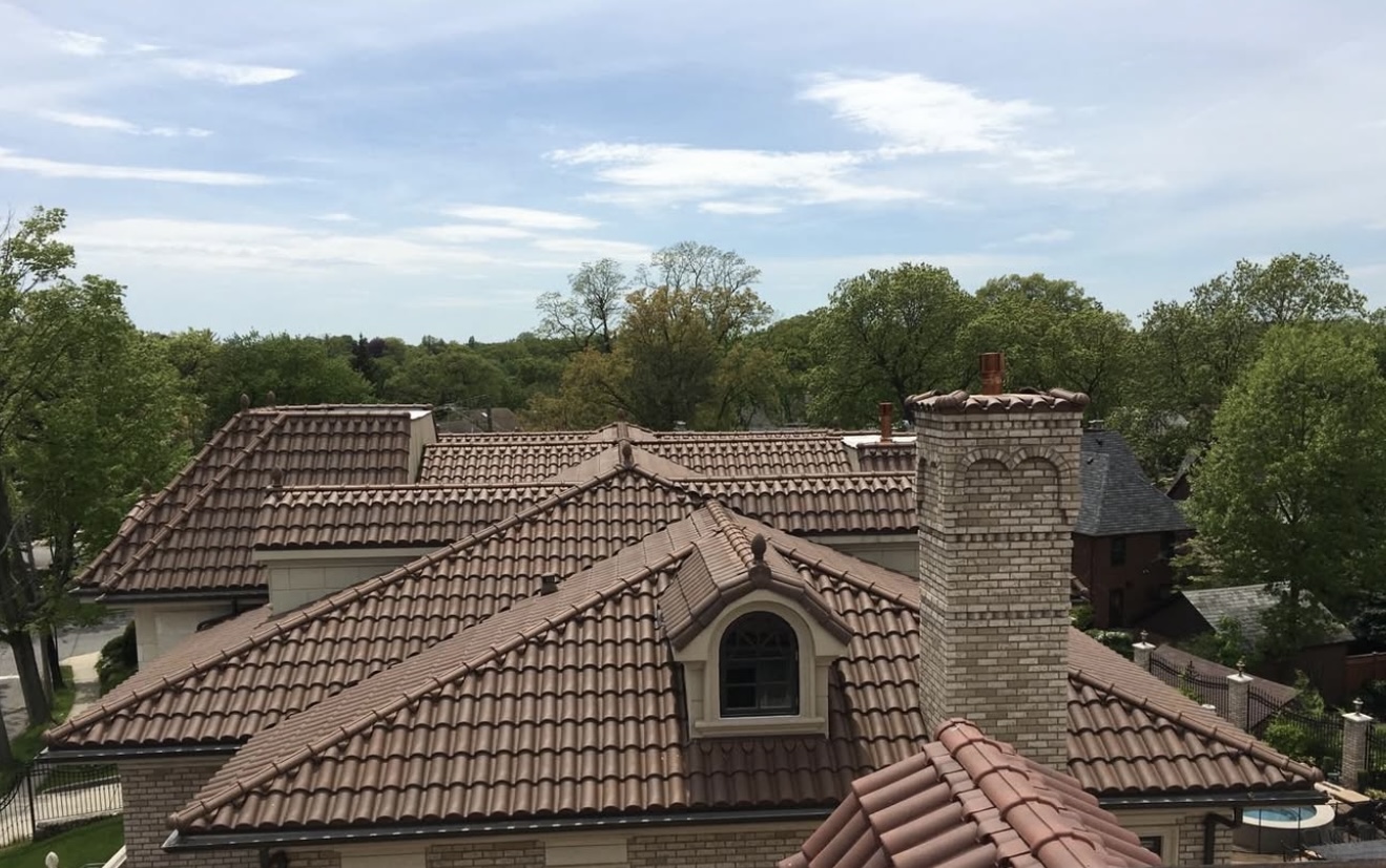 Large home with a complex roofline featuring walnut brown flat profile tiles.