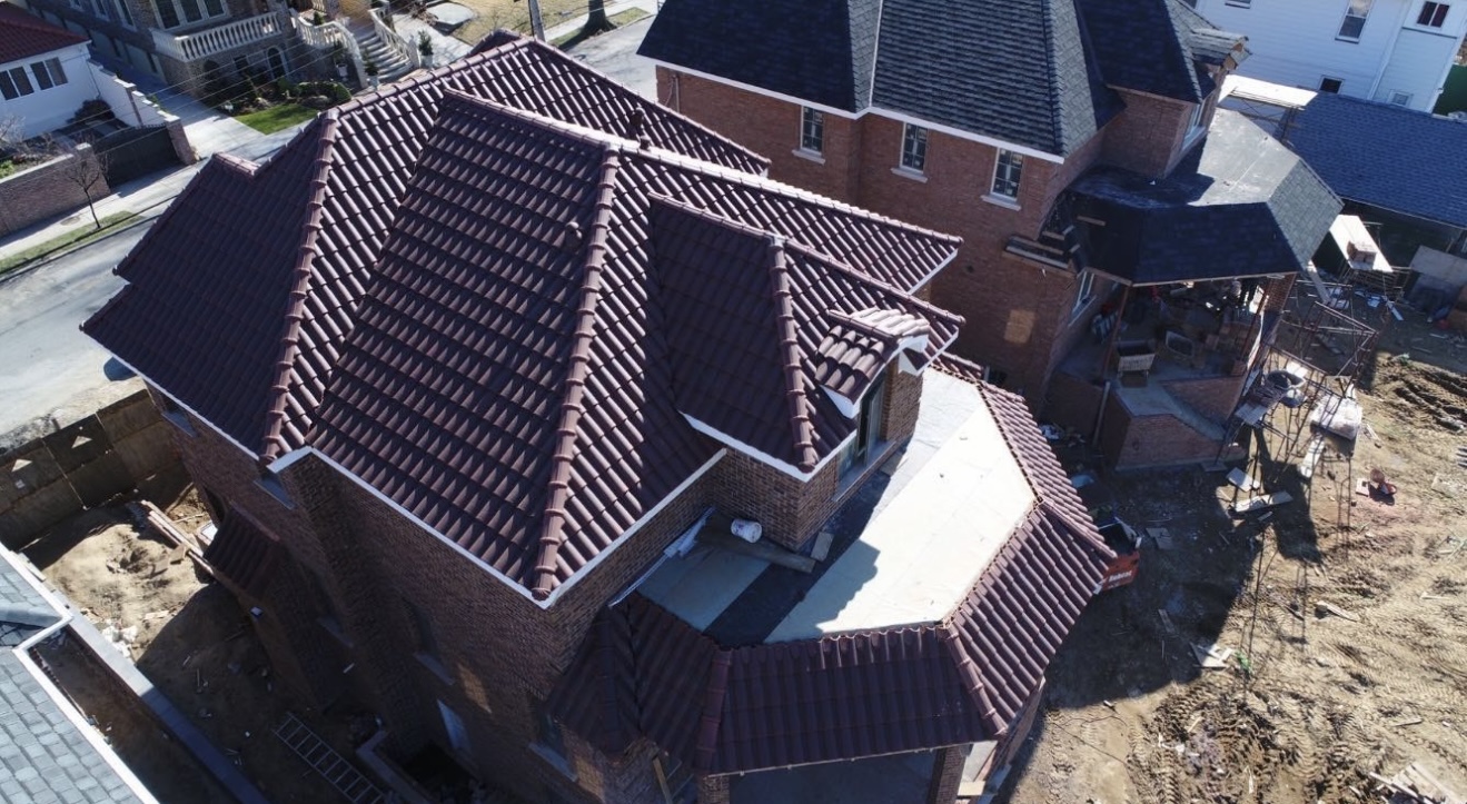 Aerial view of a new construction with a deep maroon mission barrel tile roof.