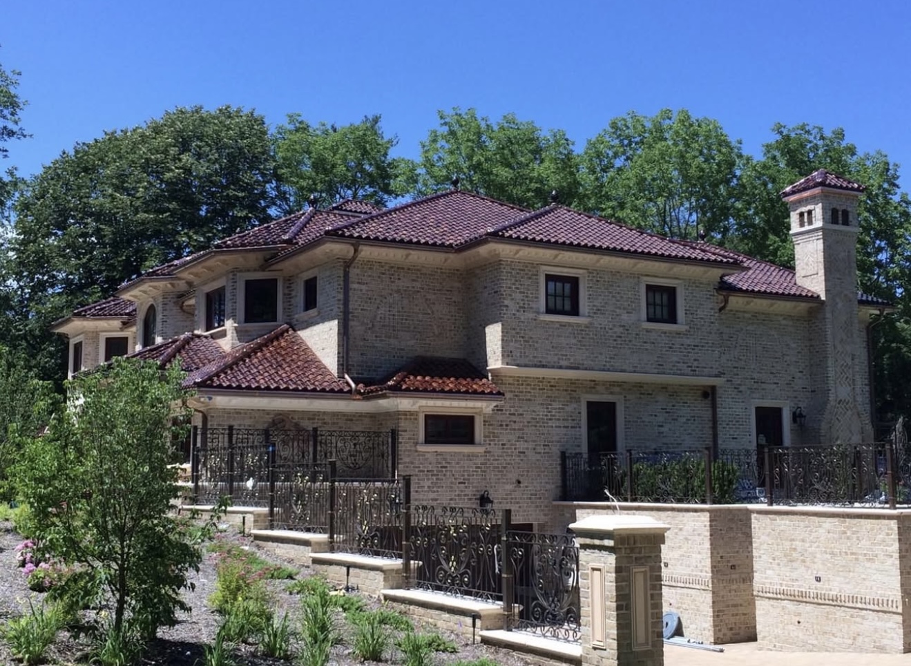 Luxury villa with a vintage red mission barrel tile roof and ornate ironwork.